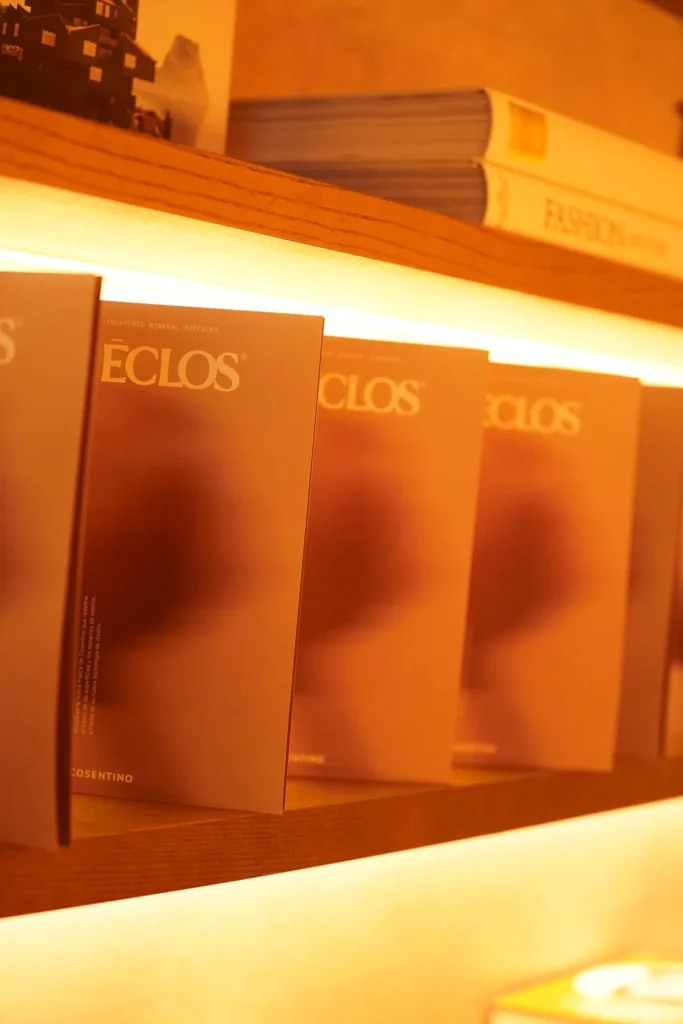 Catálogos de Eclos expuestos en una estantería iluminada