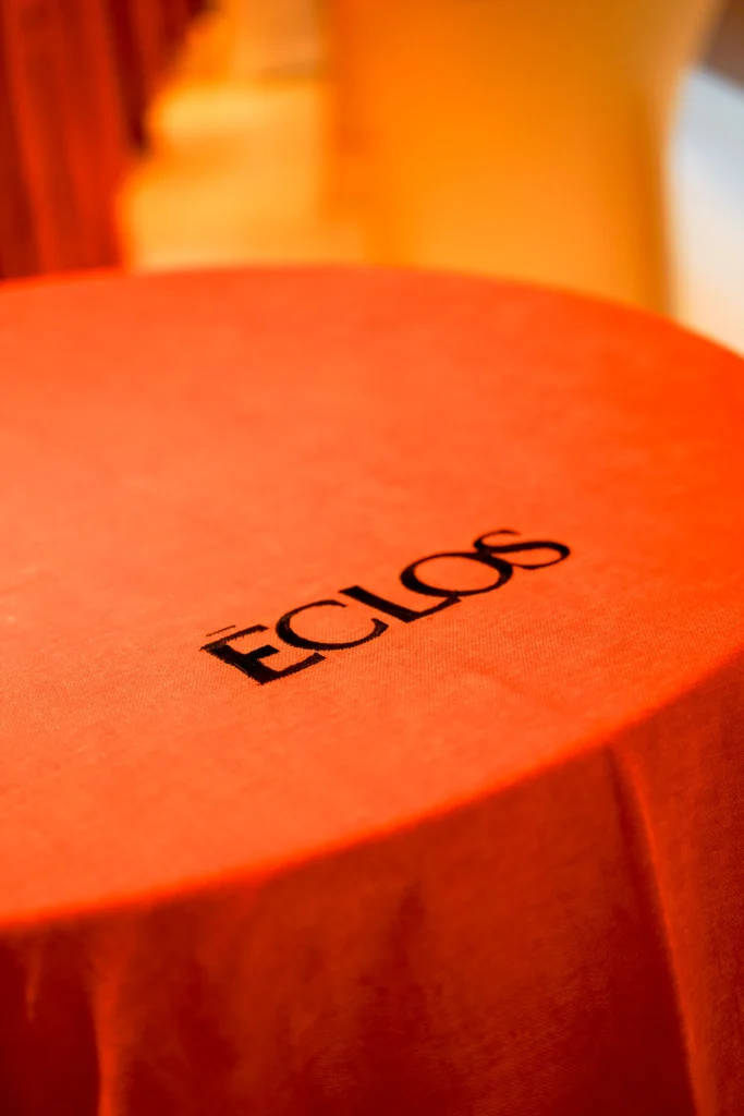 Mesa redonda con mantel naranja y el logo de Eclos