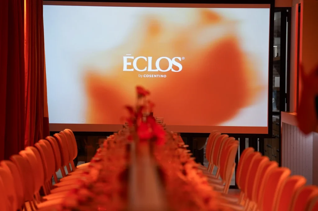 Pantalla con el logo de Eclos sobre la mesa con flores naranjas