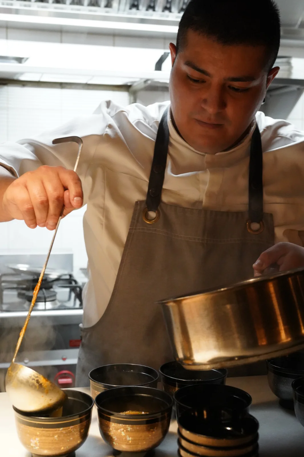 Cocinero sirviendo caldo desde un cazo de cobre en Soluna