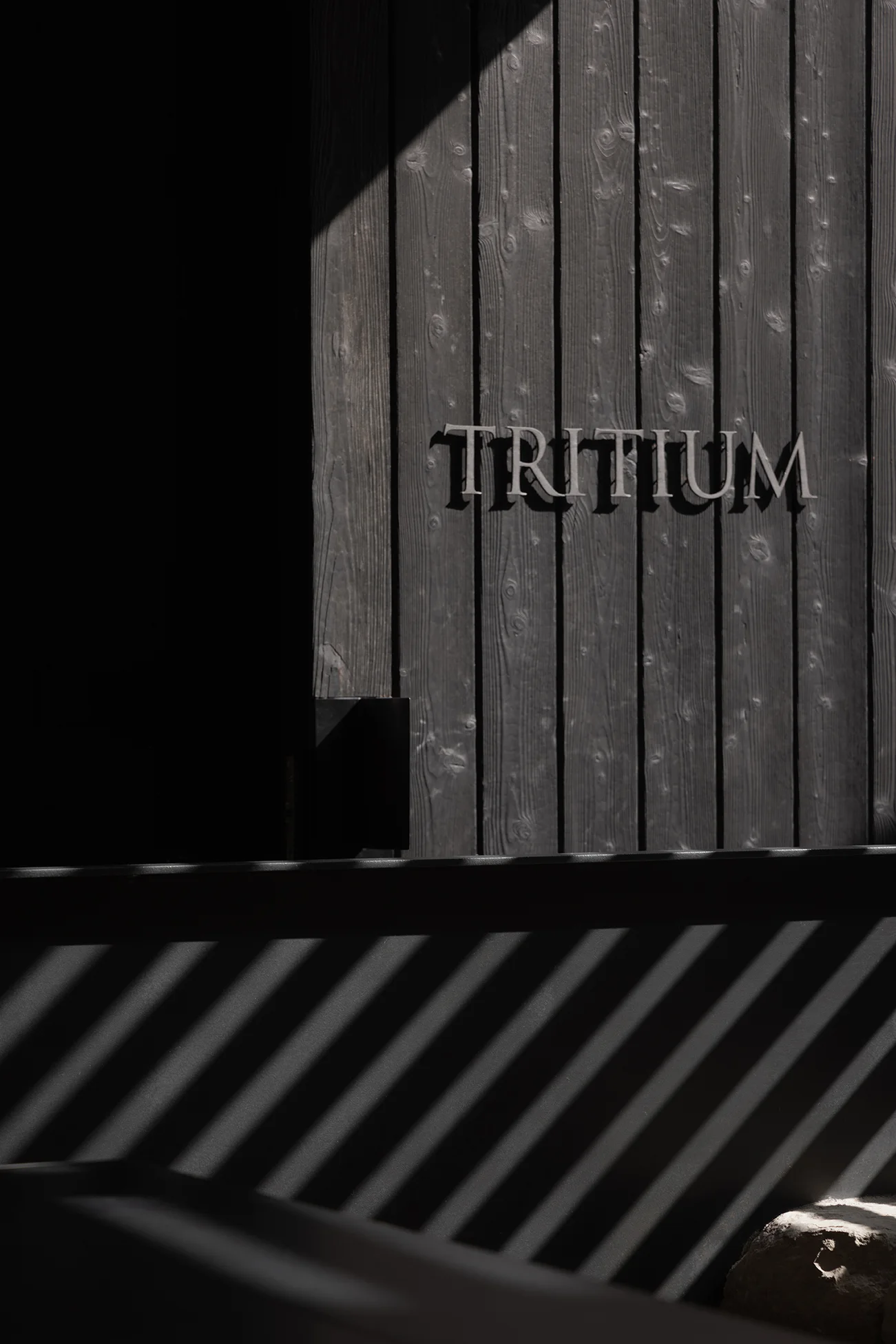 Muro de madera quemada con el nombre Tritium. Foto: Javier Márquez